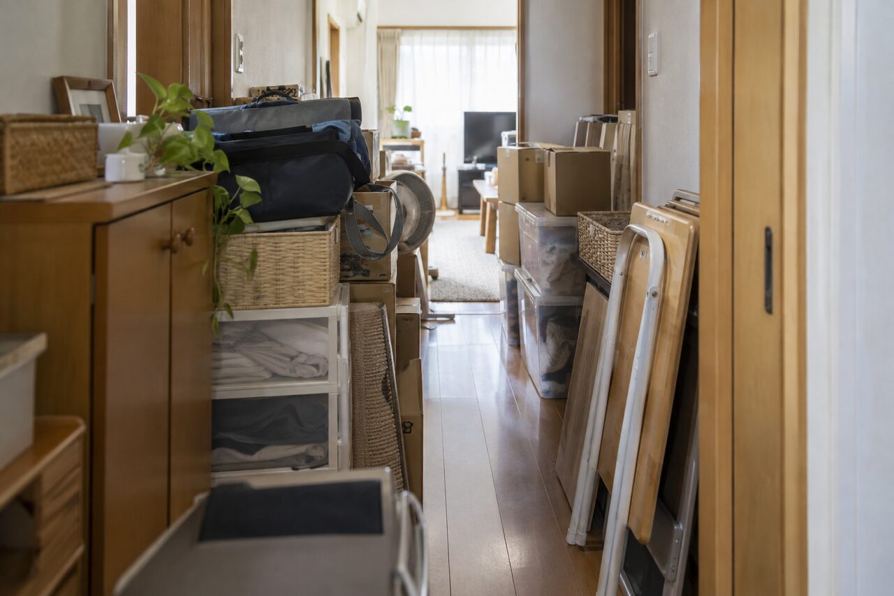 生活用品が積まれ通路が狭くなった室内、人物なし